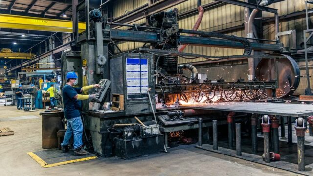 Industritekniker i SMV-segmentet arbejder ved en maskine hvor gnisterne hopper ud fra.