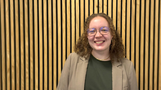 Kvinde med krøllet hår står op ad væg.